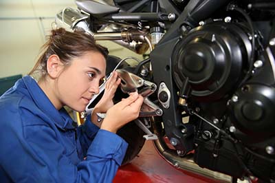 A motorcycle technician working on a motorcycle.